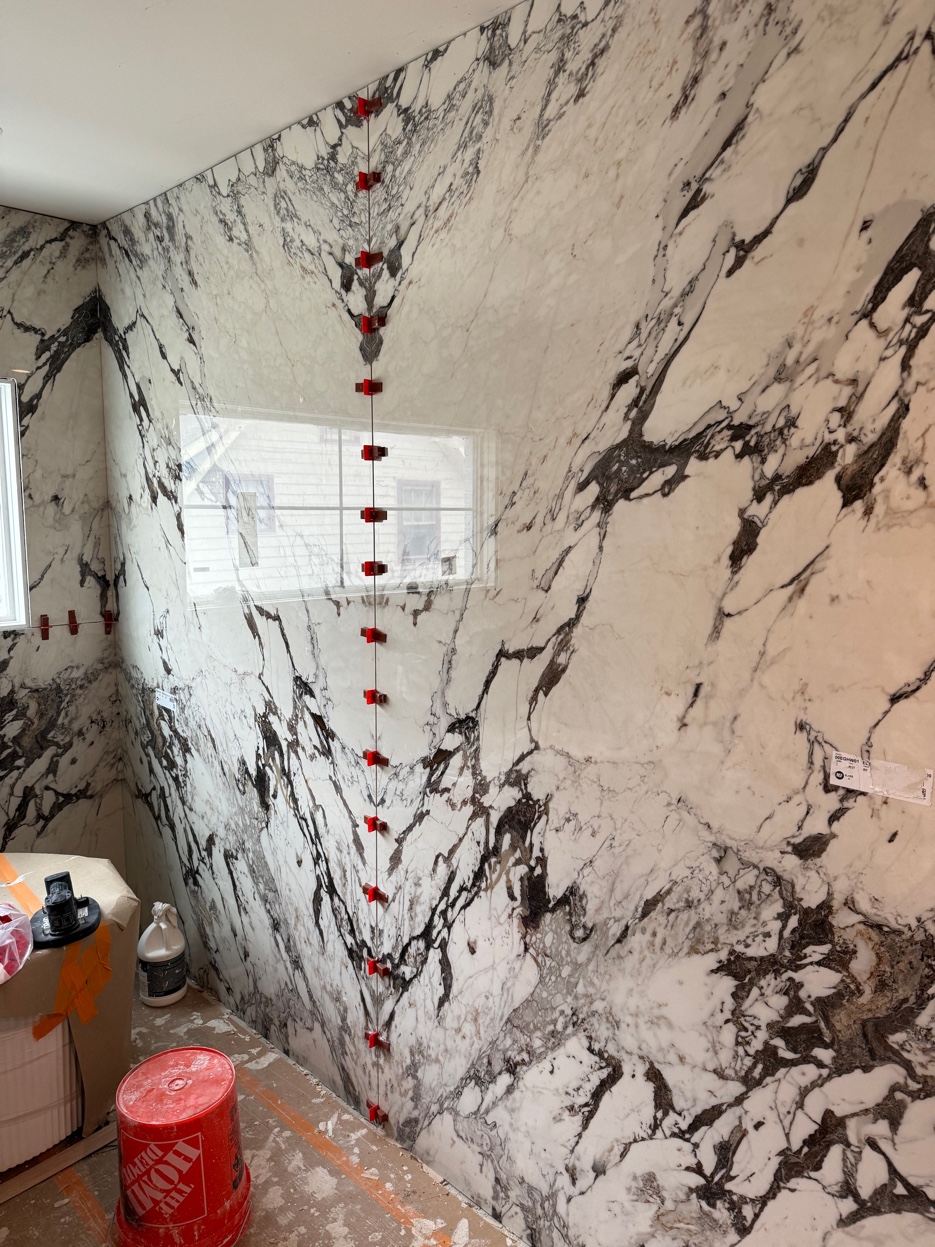 Large format marble shower walls going up installation process Chicago